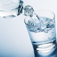 pouring water into glass from a bottle, on blue background